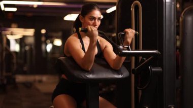Spor salonundaki bir kadın modern bir spor salonunda vaiz kıvrımlı makinesinde biseps egzersizi yapıyor..