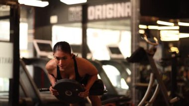 Atletik kadın göğsünde plakayla ağırlık geliştirme egzersizi yapıyor.