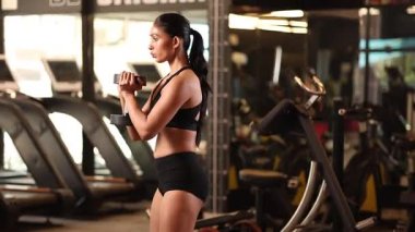 Formda bir dişi spor salonunda halter egzersizi yapar. Güç ve dayanıklılığa odaklanır..