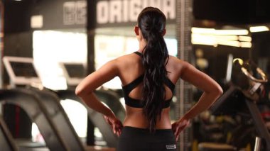 Kaslı vücutlu bir kadın kameraya özgüven ve zarafetle bakar..