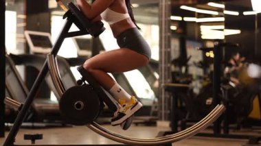 Sağlıklı bir kadın spor salonunda vücut kuvveti ve dayanıklılığına odaklanarak Ab Coaster icra eder..