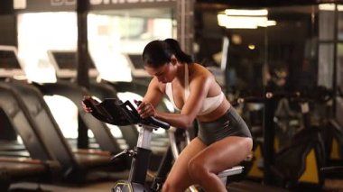 Spor kıyafetli genç bir bayan sporcu sabahları bisiklet sürüyor, dayanıklılık ve zindeliğe odaklanıyor..