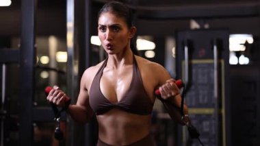 Formda bir kadın spor salonunda güçlü ve odaklanmış bir şekilde halat çapraz egzersizi yapar..