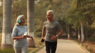 Huzurlu bir park ortamında iki son sınıf öğrencisi sabah koşuları sırasında gülüşlerini ve motivasyonlarını paylaşıyorlar..