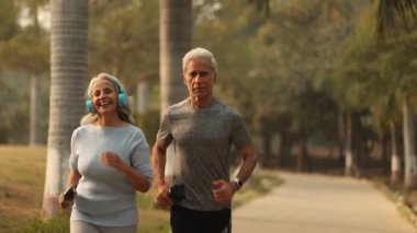 Güzel Hintli çift parkta birlikte koşuyor, egzersiz rutinlerinin tadını çıkarıyor ve sabahları dışarıda aktif kalıyorlar..