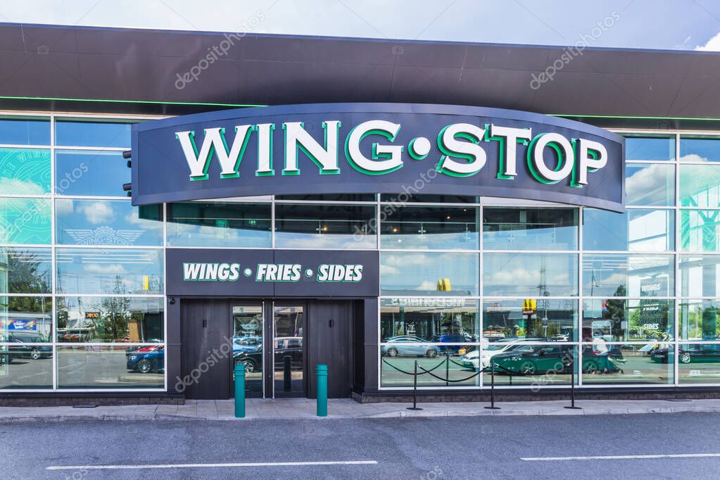 Facade of a Wingstop restaurant with bold logo and glass windows in daylight. London, UK, 28 July 2024