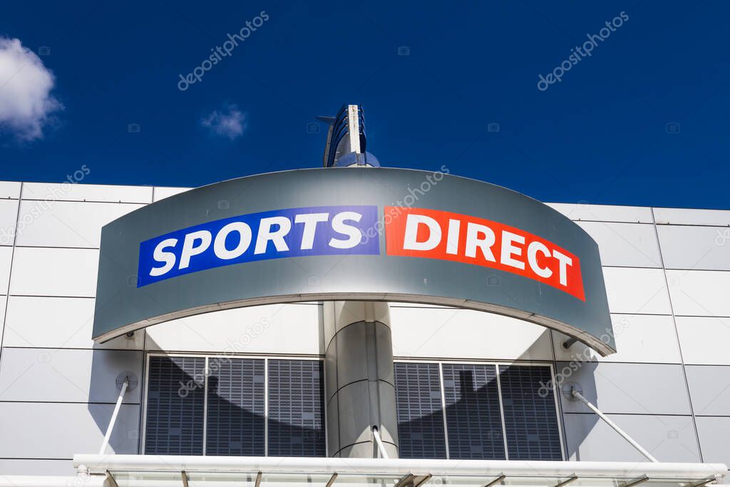 Sports Direct exterior with bold logo on a curved entrance canopy under clear sky. London, UK, 28 July 2024