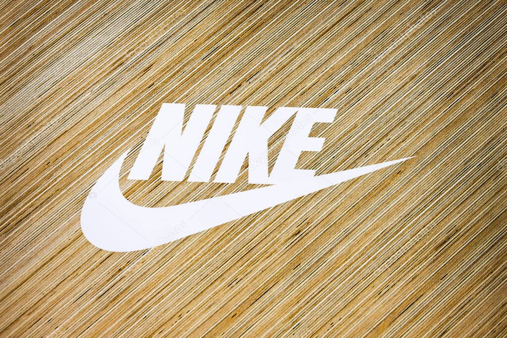 Minimalist white Nike wordmark and swoosh on warm wood. London, UK, 28 July 2024