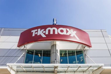 Kırmızı TK Maxx logosu, cam girişi ve mavi gökyüzü olan çağdaş bir cephede. Londra, İngiltere, 28 Temmuz 2024