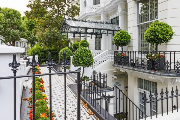 Süslü, işlemeli demir parmaklıklar ve cam konservatuarla döşenmiş beyaz bir teras..