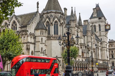 Londra 'daki Kraliyet Adalet Divanı' nda Gotik Diriliş mimarisi ve kırmızı bir otobüs yer alıyor. Londra, İngiltere, 10 Ağustos 2024