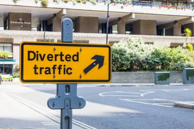 Yol kenarına yön oku yerleştirilmiş sarı yönlü trafik işareti.