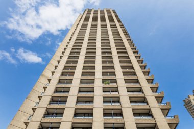 Londra, İngiltere 'deki Barbican Emlak Kulesi' nin dramatik alçak açılı görüntüsü. Vahşi beton cephe, tekrar eden balkonlar, mavi gökyüzü, modernist yerleşim yeri mimarisi..