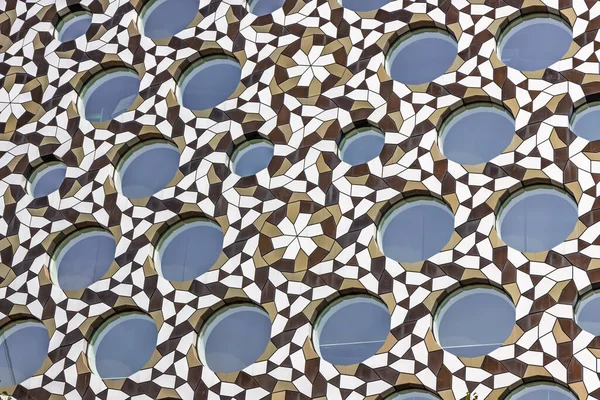 İslami yıldız çemberleri olan delinmiş bir ekranı kapatın, pencereleri gölgeleyen ve dekoratif dokularla modern bir cepheyi zenginleştiren bir mashrabiya kafesi..