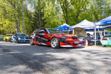 Sponsor üniformalı canlı kırmızı drift araba bir motor sporu etkinliğinde çadırların altında yer alır. Alytus, Litvanya, 25 Mayıs 2025