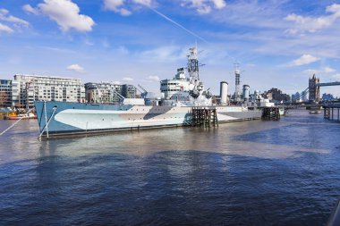 HMS Belfast, tarihi bir Kraliyet Donanma kruvazörü, Thames Nehri 'ne Tower Bridge tarafından demirlenmiş, Londra silueti tarafından çerçevelenmiş ve berrak bir günde sakin su yansımaları. Londra, İngiltere, 11 Mart 2023