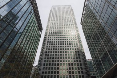 Londons Canary Wharf 'taki modern cam gökdelenin düşük açılı görüntüsü, büyük bir finans bölgesindeki kurumsal mimari ve yansıtıcı pencereleri vurguluyor. Londra, İngiltere, 16 Nisan 2023