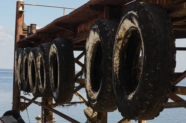 Wooden pier on the river close-up. On the side of the pier are old automobile tires. Old boat mooring on the river.