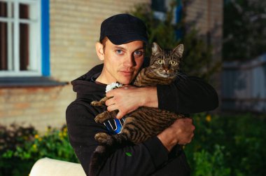 Spor giyim bölümündeki yakışıklı adam. Hayvanınla yürü. Favori hayvan kedi..