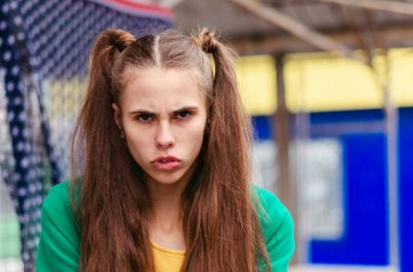 Genç bir kız, yeşil bir ceket giymiş, parlak ve neşeli. Okul çocukları için tatil. Duyguların yüzünde, hoşnutsuzluk, soru, öfke.