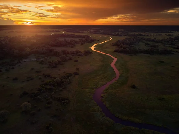 Sunset, aerial, atmospheric view on curving river Khwai, Moremi forest, Botswana. Typical ecosystem, part of Okavango delta, aerial photography. Vast wilderness without people, animal paradise.Africa.