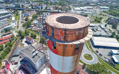Baca temizliği. Isıtma tesisi endüstriyel baca, yüzlerce metre yüksekliğinde. Arka planda baca ve şehrin üst havadan görünümü. Enerji endüstrisi, hava kirliliği.