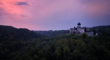 Çek Cumhuriyeti'nin Moravya şehrinin en büyük kalelerinden biri olan Sovinec, Eulenburg, sağlam ortaçağ kalesinin havadan görünümü. Dramatik, turuncu gökyüzüne karşı kayalık bir tepe üzerinde ortaçağ kale ile Çek manzara.