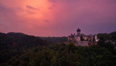 Çek Cumhuriyeti'nin Moravya şehrinin en büyük kalelerinden biri olan Sovinec, Eulenburg, sağlam ortaçağ kalesinin havadan görünümü. Dramatik, turuncu gökyüzüne karşı kayalık bir tepe üzerinde ortaçağ kale ile Çek manzara.