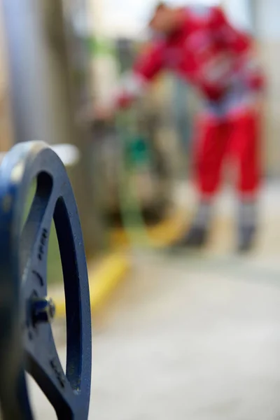 Heating valve control wheel. Blurred background. A technician in red overalls is servicing heating technology. Start of hot water supply into  big city heating network. Heating season coming.