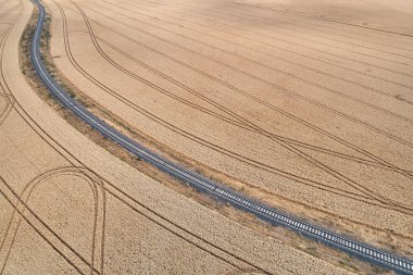 Olgun mısır tarlaları arasında kıvrılan bir demiryolu hattının havadan görünüşü. Merkez Bohemya 'da tarım arazisi. Kırsal bölgelerdeki çizgiler.