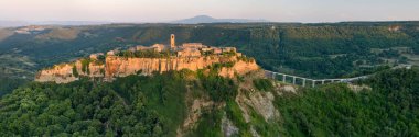 Civita di Bagnoregio. Panoramik, batan güneşle aydınlatılan antik İtalyan köyünün kaya platosunda duruşu. Tiber Nehri Vadisi üzerindeki kayalık şehir. İtalya.
