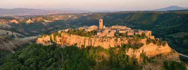 Civita di Bagnoregio. Panoramik, batan güneşle aydınlatılan antik İtalyan köyünün kaya platosunda duruşu. Tiber Nehri Vadisi üzerindeki kayalık şehir. İtalya.