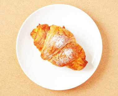 Kruvasan kremsi ahşap arka plan üzerinde beyaz tabakta. Üstten görünüm