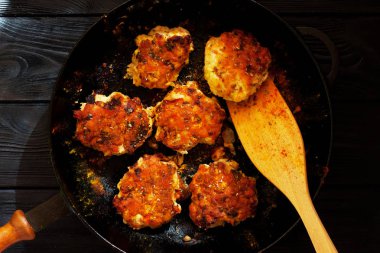 Koyu ahşap arka plan üzerinde bir tava içinde baharatlar köfteyle. Üstten görünüm. Kopya alanı.