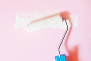 Pembe duvar yanındaki beyaz boya ile silindir