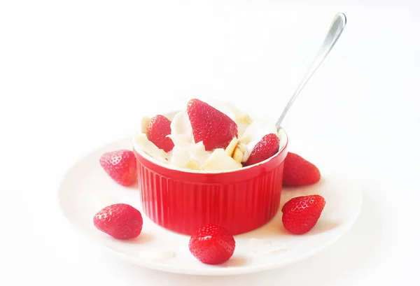 Healthy raw vegan dessert - banana and strawberry with coconut cream and coconut chips on white background