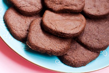 Çikolata kurabiye pembe bir arka plan üzerinde mavi plaka üzerinde. Üstten görünüm. Düz yatıyordu. Modern gıda kavramı.