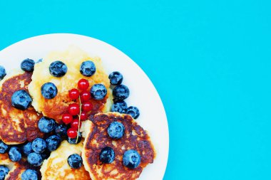 Yaban mersini ve mavi arka plan, kahvaltı veya öğle yemeği kırmızı kuş üzümü ile süzme peynir krep