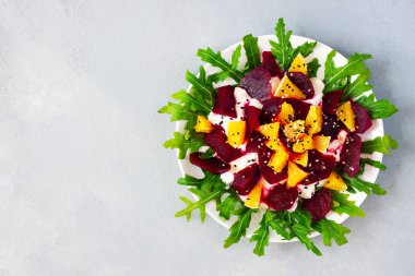 Roka, pancar, portakal ve keçi ile sağlıklı çiğ vegan salatası peynir zeytin yağı ve bal gri arka plan - sağlıklı gıda kavramı üzerinde ile ilişkili