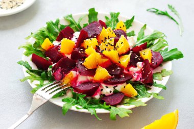 Roka, pancar, portakal ve keçi ile sağlıklı çiğ vegan salatası peynir zeytin yağı ve bal gri arka plan - sağlıklı gıda kavramı üzerinde ile ilişkili