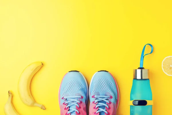 Fitness kreativer Hintergrund - Flasche mit Zitronenwasser, Fitness-Tracker, Banane und Snickers auf gelbem Hintergrund, flache Lage, Kopierraum — Stockfoto
