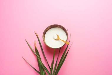 Kasede kolajen tozu ve pembe arka planda palmiye yaprakları. Fazladan protein alımı. Cilt ve kemikler için doğal güzellik ve sağlık desteği. Bitki bazlı kolajen konsepti. Düz yerde, üst tarafta. Boşluğu kopyala.
