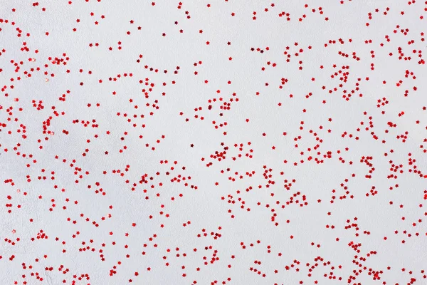 Rotes Konfetti auf grauem Hintergrund. Weihnachten, Winter, Neujahr. Flache Lage, Draufsicht — Stockfoto