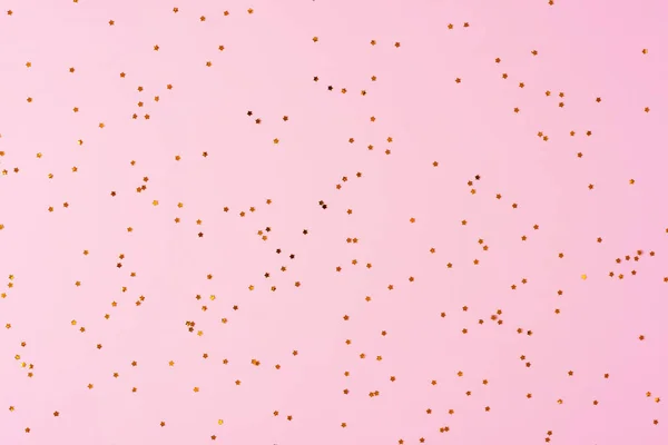 Goldenes Konfetti auf rosa Hintergrund. Weihnachten, Winter, Neujahr. Flache Lage, Draufsicht — Stockfoto