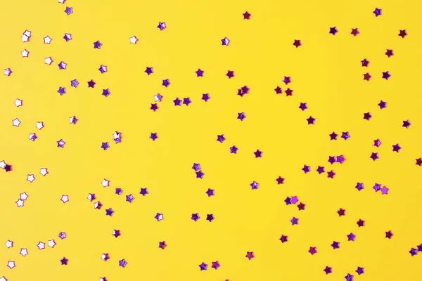 Fialové konfety na žluté. Barevné vánoční nebo prázdninové pozadí — Stock fotografie