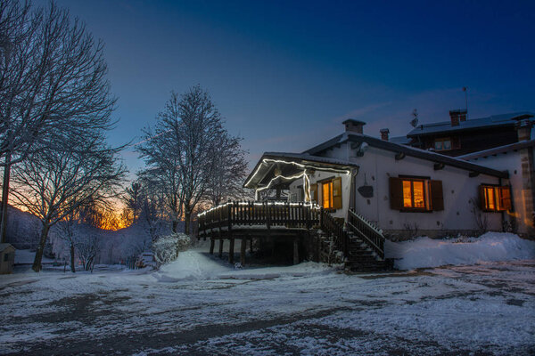 Hut after a snowfall at sunset