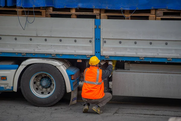 Lastbilschaufför säkrar lastning av flaskor mineralvatten av binda med rep innan transport — Stockfoto