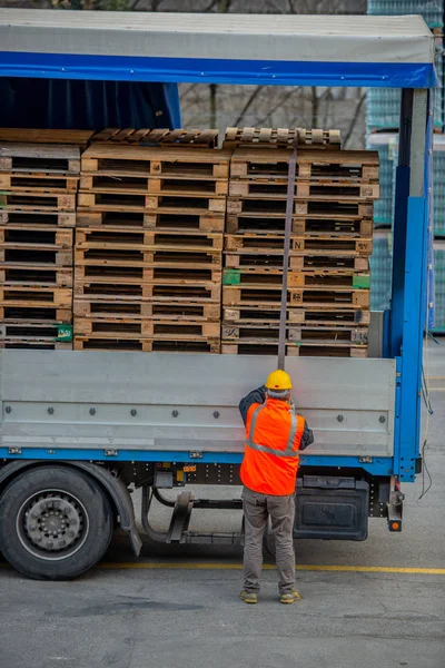 LKW-Fahrer sichert die Verladung von Mineralwasserflaschen, indem er sie vor dem Transport mit Seilen bindet — Stockfoto