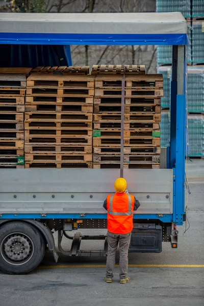 Lastbilschaufför säkrar lastning av flaskor mineralvatten av binda med rep innan transport — Stockfoto