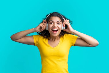 Hoş giyinmiş, kablosuz kulaklıklı kız heyecanlı bir ağızla müzik dinliyor..